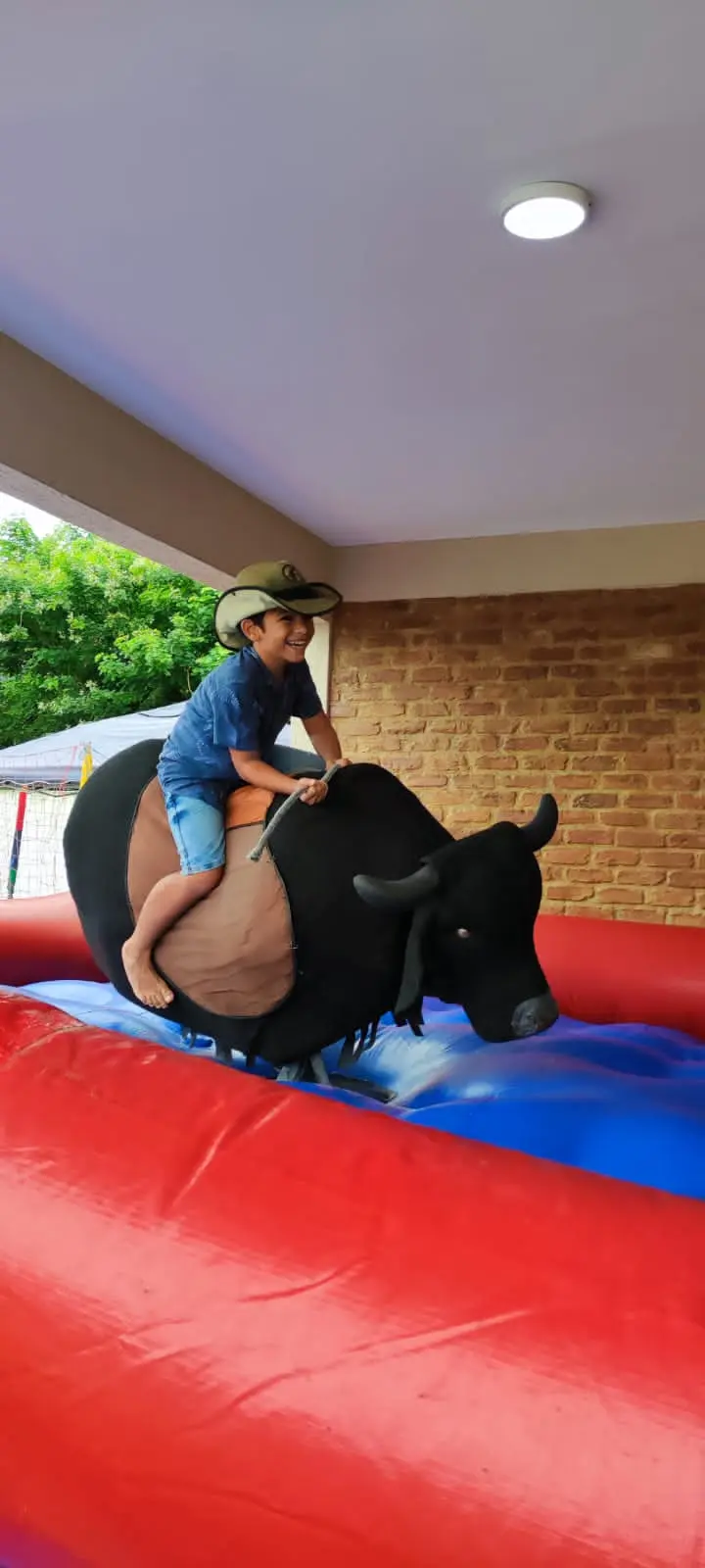Criança com chapéu de cowboy andando no touro mecânico do Pula Magia
